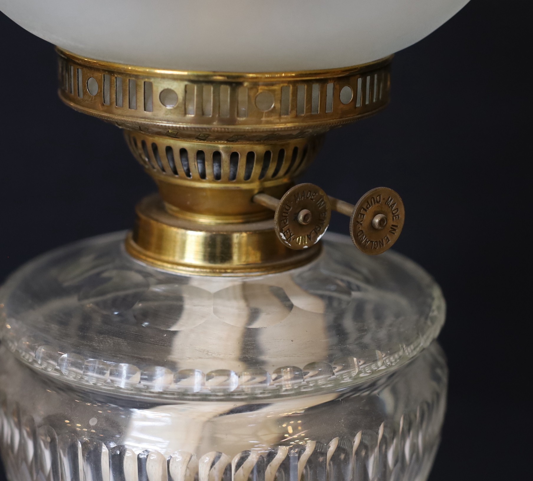 A late Victorian brass oil lamp with cut glass reservoir, duplex mechanism, etched glass globe and flue, height overall 68cm